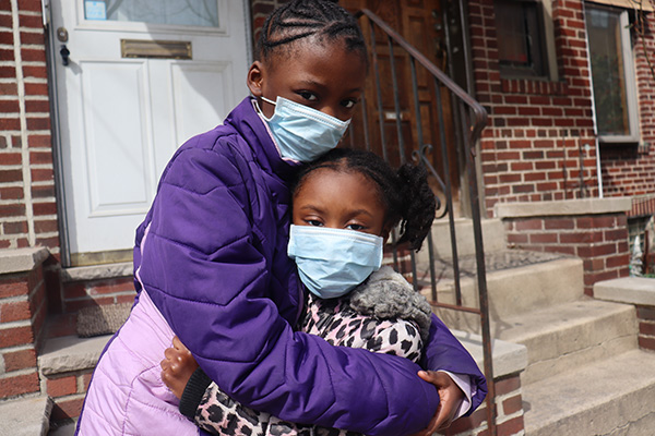 2 girls wearing masks and hugging